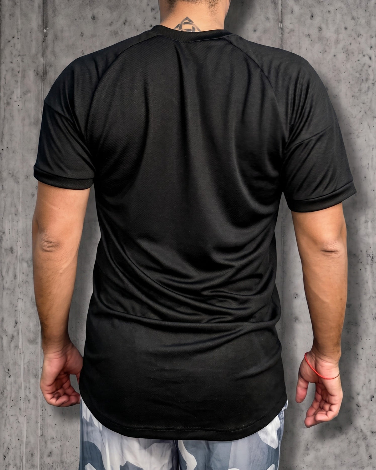 Vista de espalda de la camiseta deportiva negra para hombre, mostrando la textura de la tela y la caída relajada.