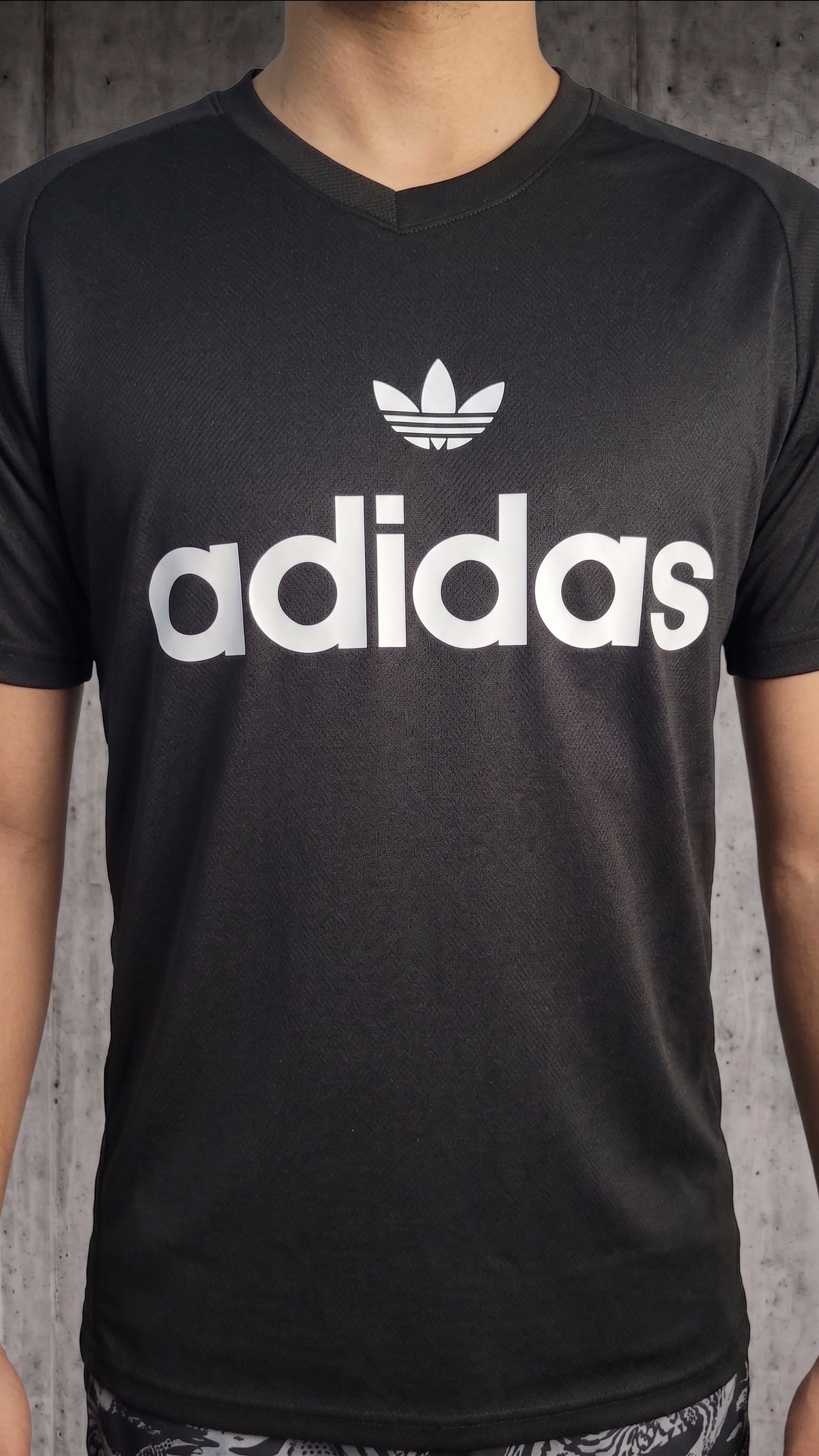 Vista frontal completa de hombre usando camiseta deportiva negra con cuello en V y logo clásico blanco en el pecho.