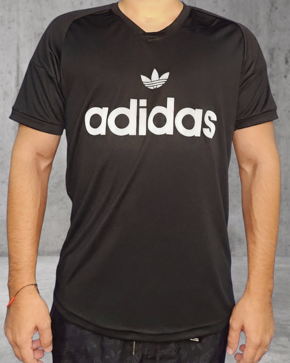 Vista frontal completa de hombre usando camiseta deportiva negra con cuello en V y logo clásico blanco en el pecho.