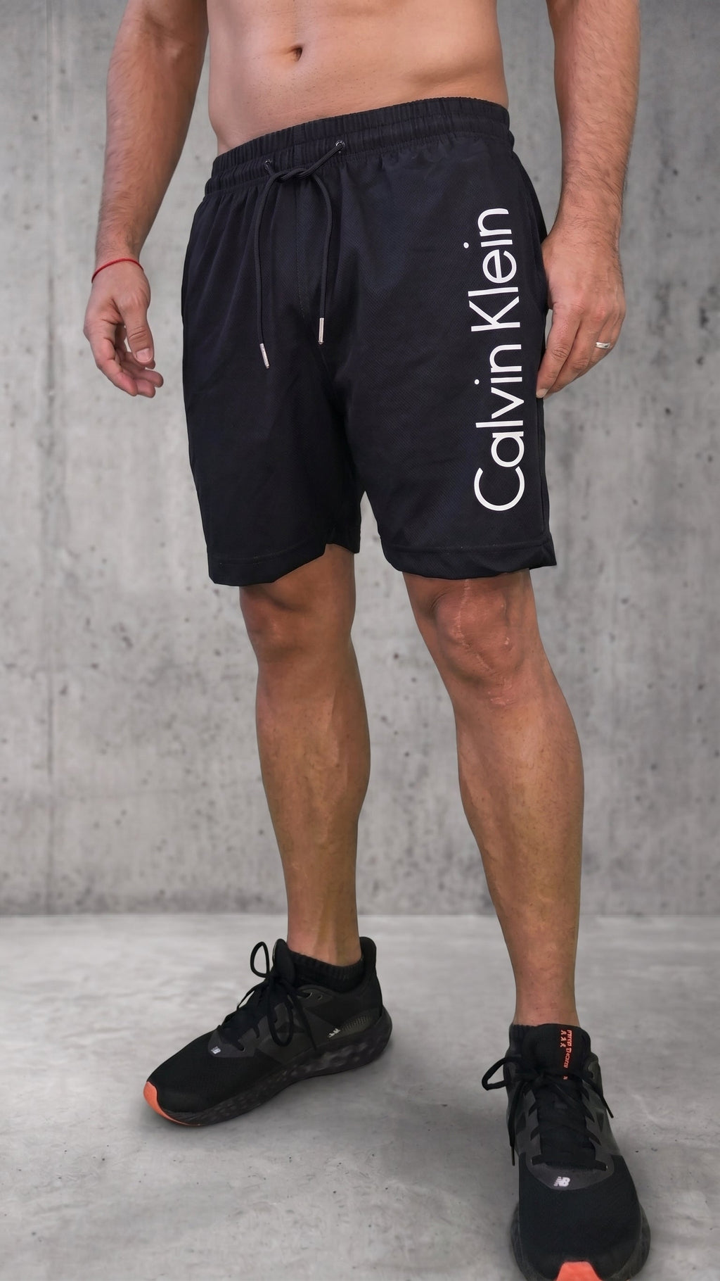 Bermuda deportiva negra con texto blanco vertical en la pierna izquierda
