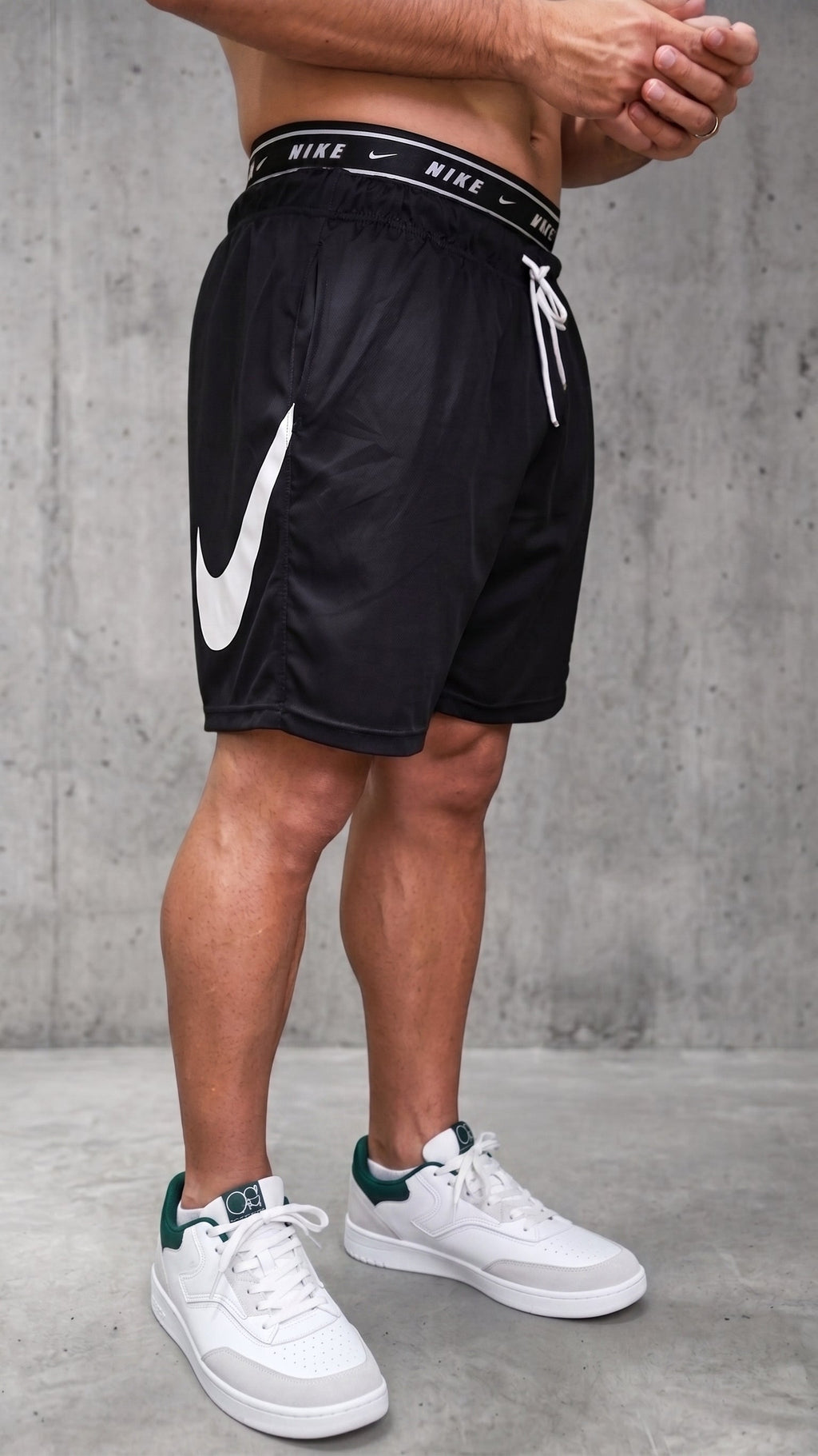 Bermuda deportiva negra para hombre con pretina expuesta y cordones blancos vista diagonal