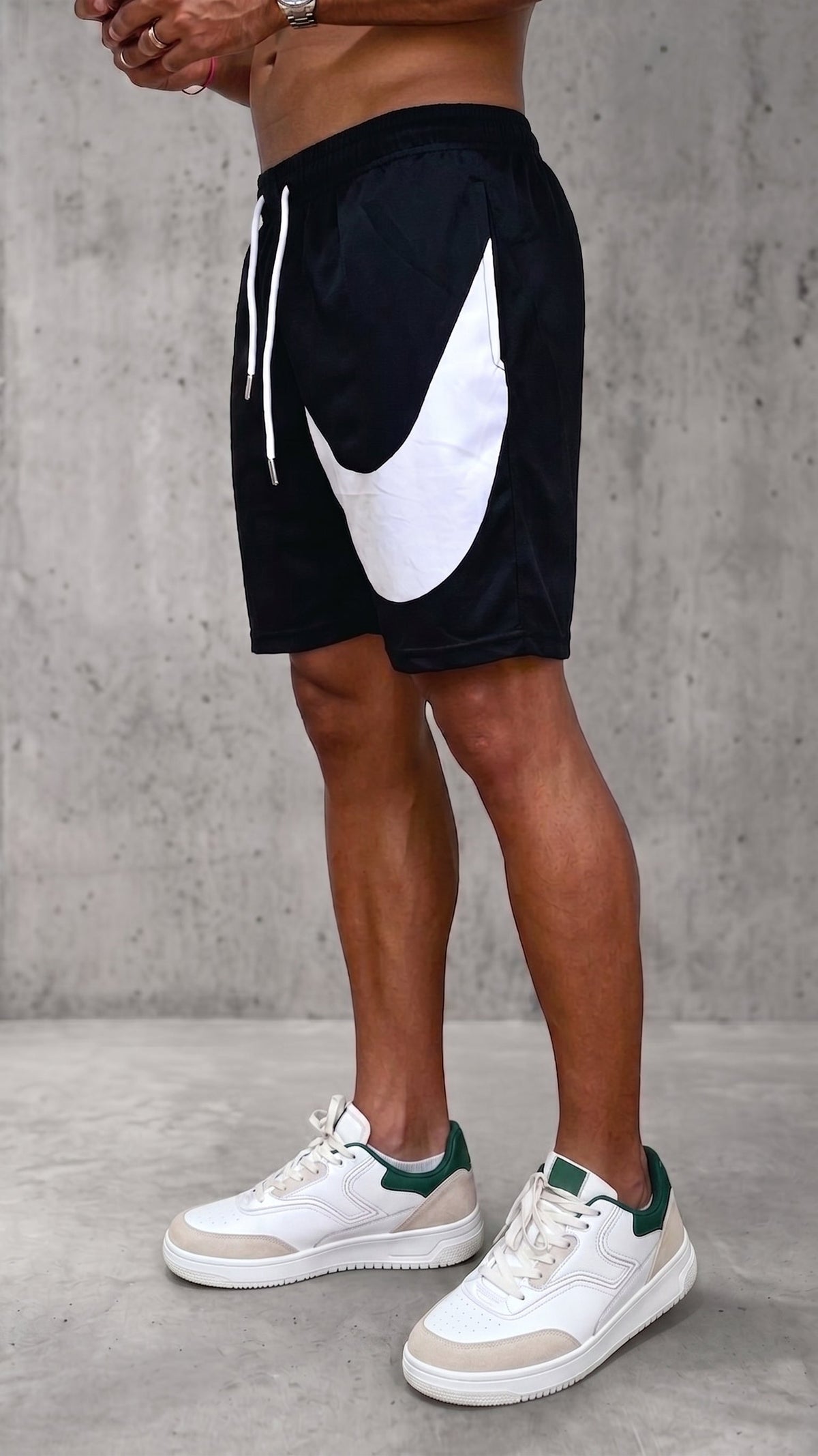 Pantaloneta urbana hombre negra con gran simbolo curvo blanco en la pierna vista diagonal