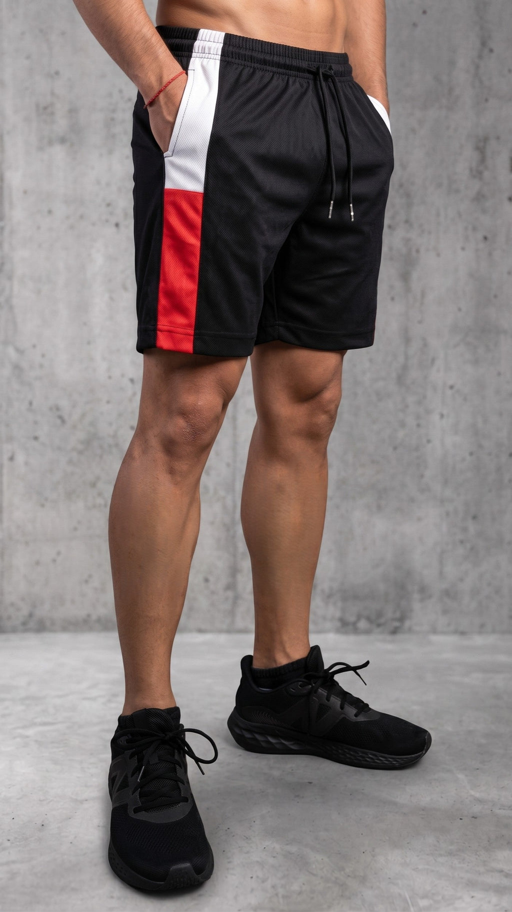 Pantaloneta deportiva para hombre en color negro con bloques laterales en blanco y rojo, modelo con cordón ajustable y bolsillos laterales